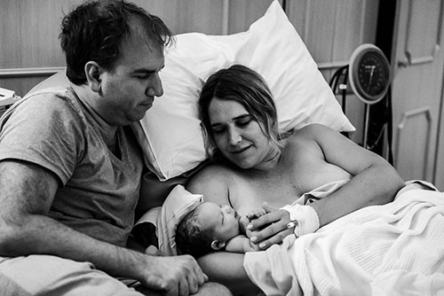 New mum holding newborn baby with the father