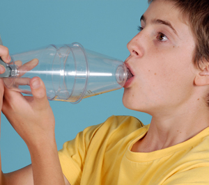 Person inhaling from large volume spacer